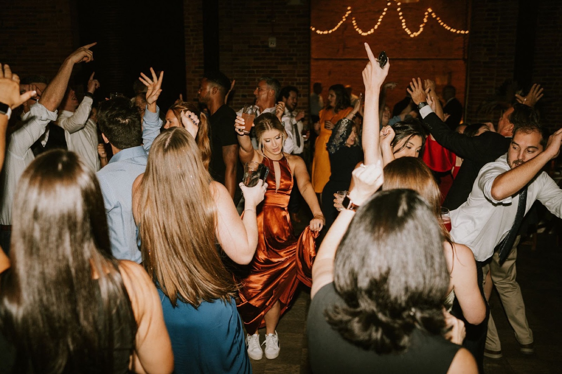 Guests with their arms raised on a packed dance floor