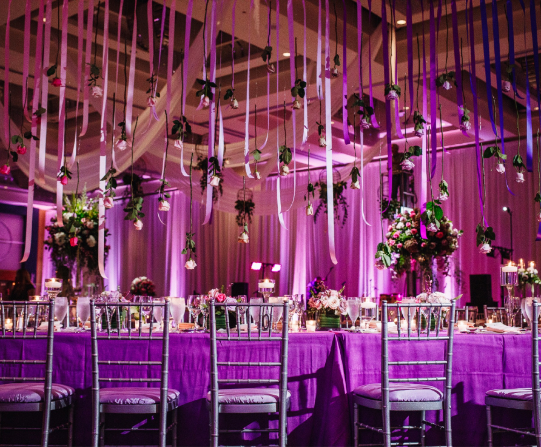 A ballroom set for a reception under purple uplighting